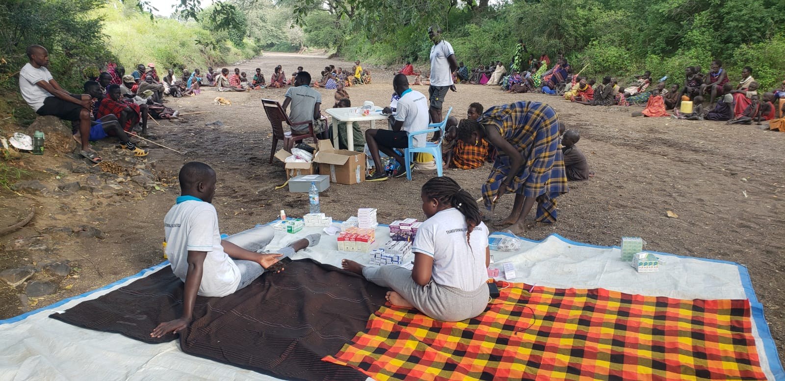 Medical Mission team providing care at an outdoor mobile clinic, with community members gathered nearby.
