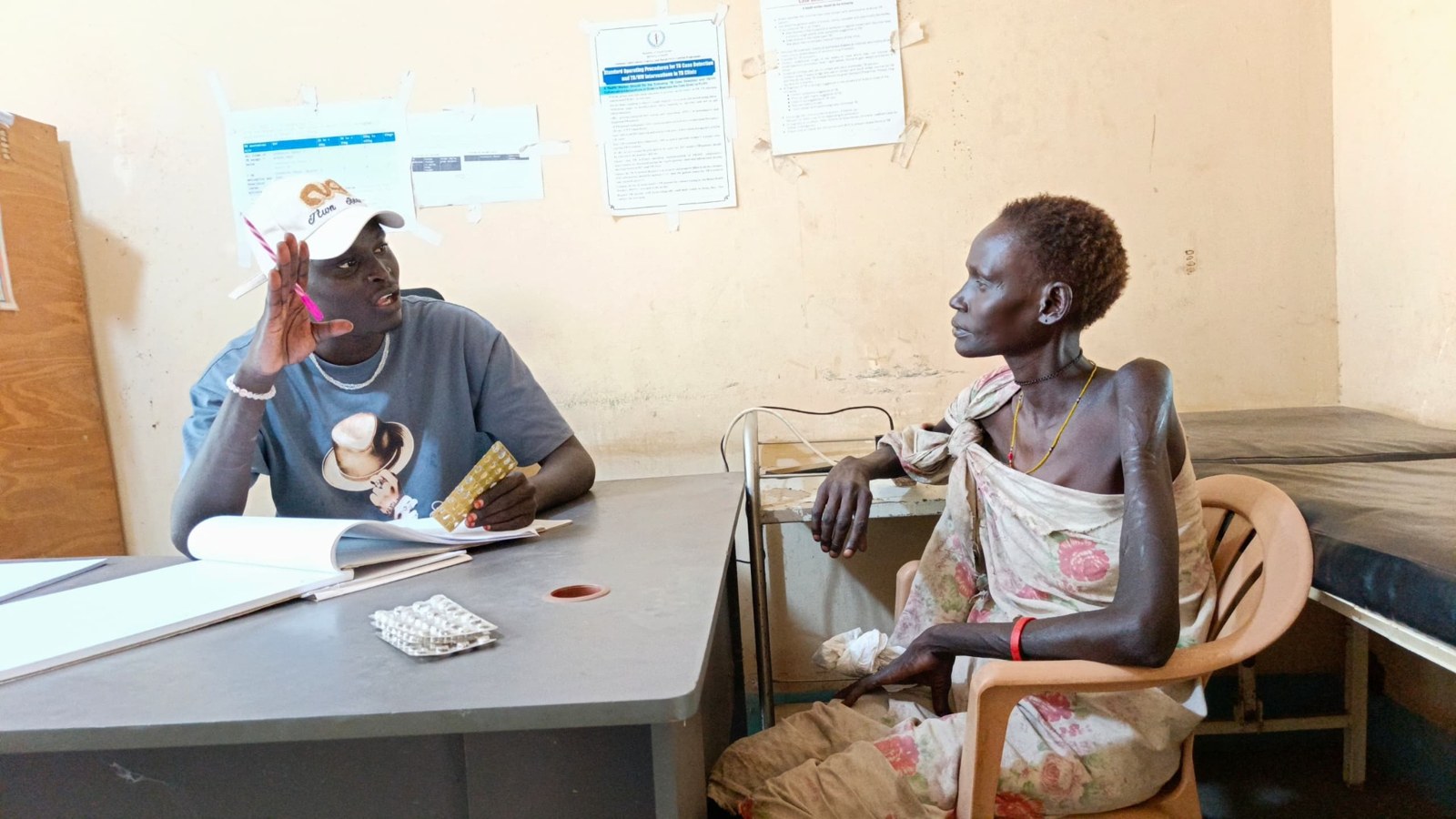 A health worker discussing medicines with a community member during a consultation.